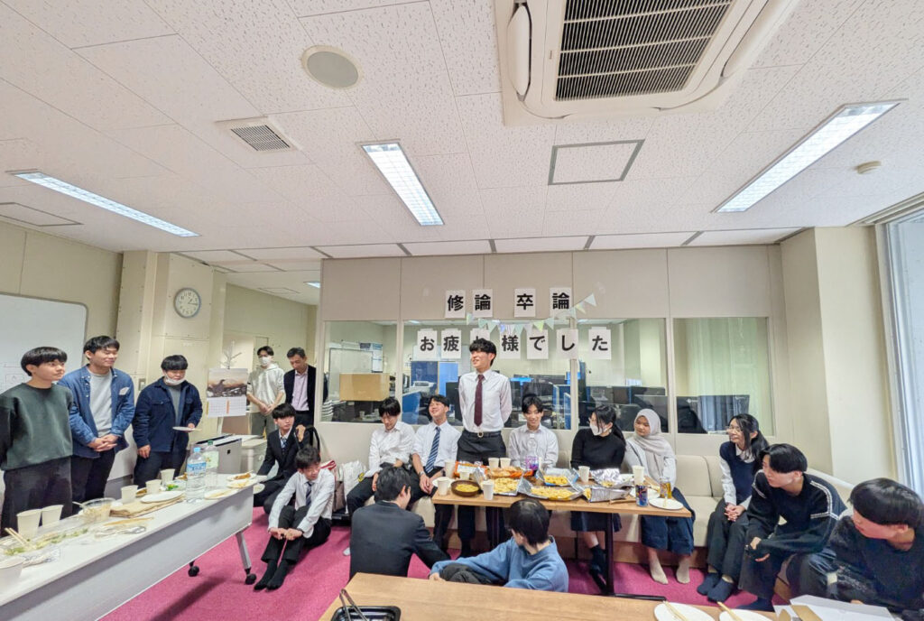 前で話す学部生と話を聞く先生と学生